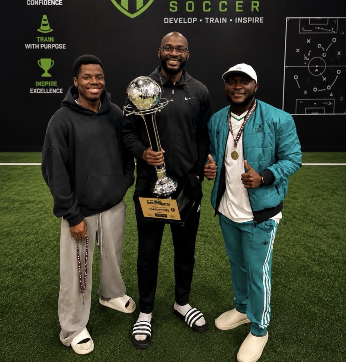 Coach Arnold holding the indoor league champions trophy with two teammates